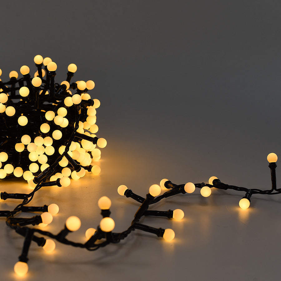 Dettaglio_Catena_500_LED_a_Sfera_Arrotolata_Accesa_Luce_Calda_su_Sfondo_Grigio